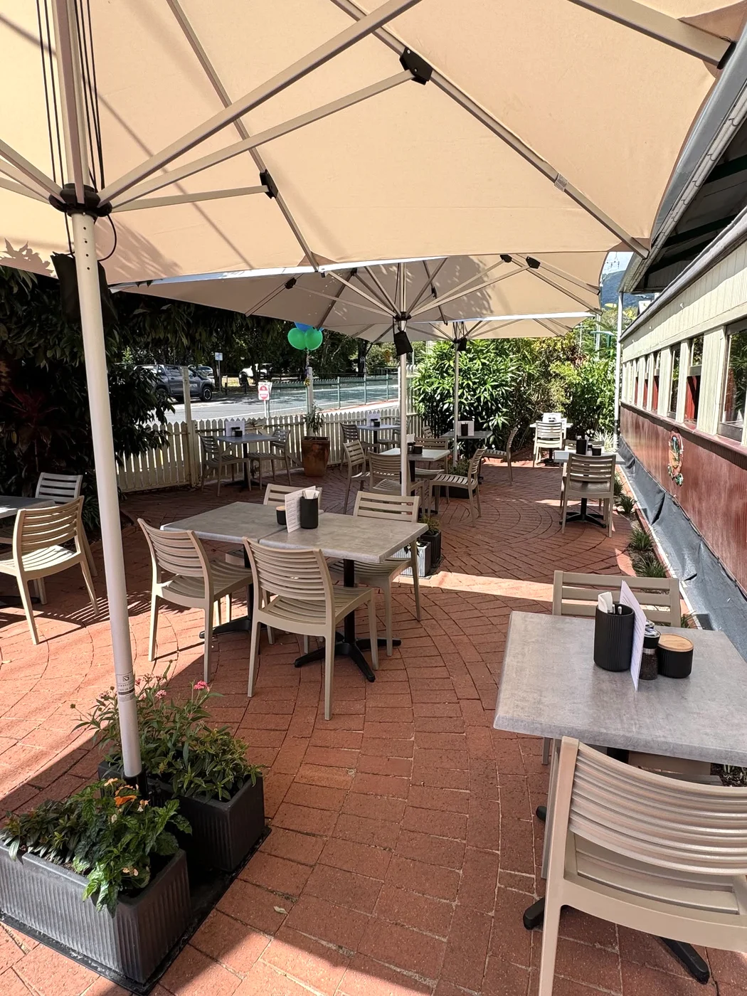 Shaded tables beneath cream umbrellas alongside the burgundy railway carriage